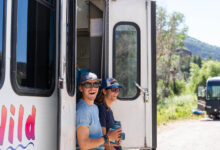 Two guide in the doorway of the bus smiling before getting on the San Miguel River