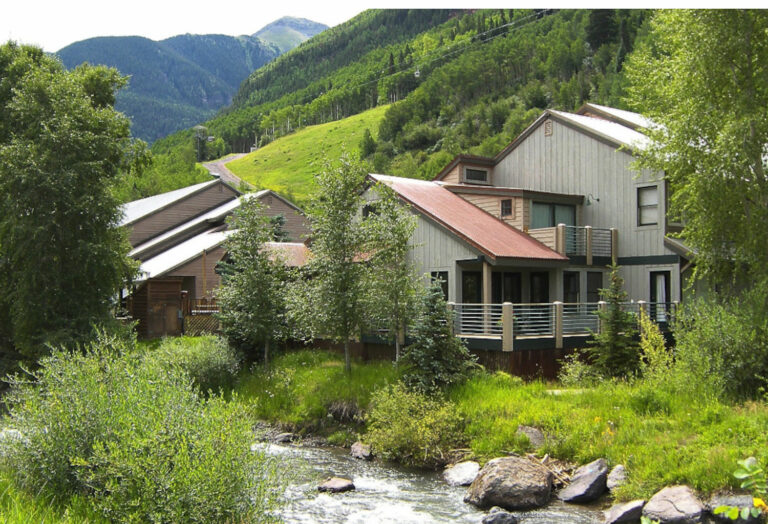 Quaint Inn situated along a creek with mountains in the background