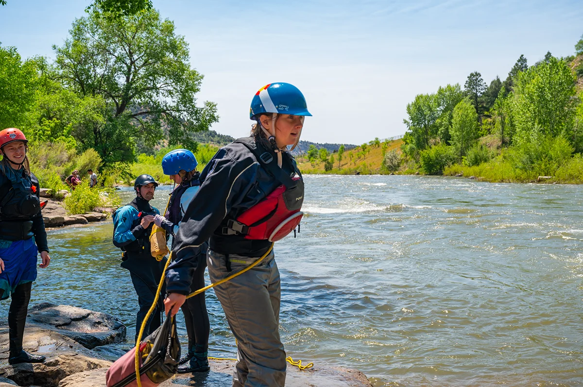 A man dressed in safety gear, preparing to river raft